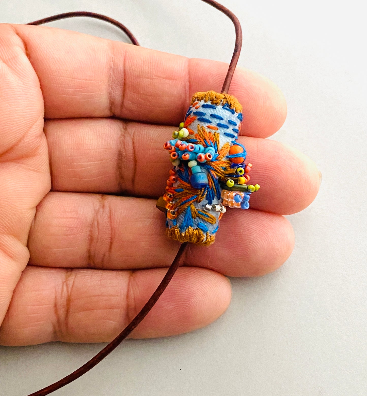 "Horizon" Blue and orange embroidered and beaded textile necklace.
